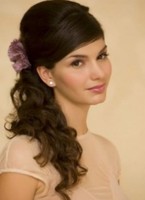 Prom half updo hairdo with curls and swept bang with cute purple flower hair clip
